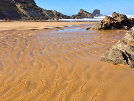 rocks on the ocean, seascape, beautiful sandy beach, clear blue sky, sunny weatherの写真素材