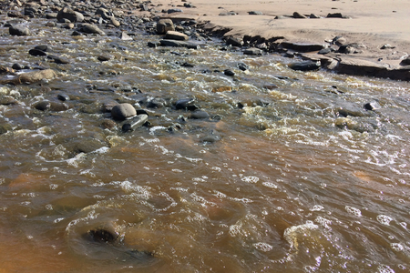 stream with muddy waters, fast flow, sandy shoreの写真素材