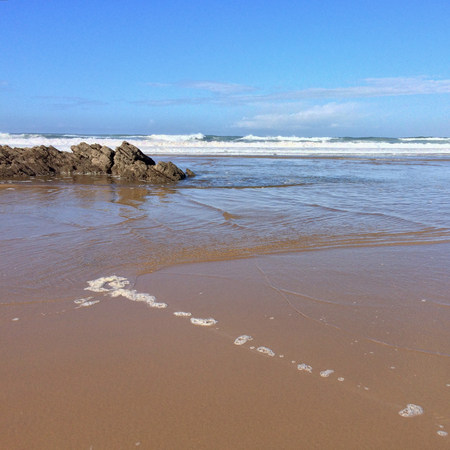 rocks on the ocean, seascape, beautiful sandy beach, clear blue sky, sunny weatherの写真素材
