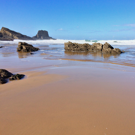 rocks on the ocean, seascape, beautiful sandy beach, clear blue sky, sunny weatherの写真素材