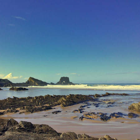 rocks on the ocean, seascape, beautiful sandy beach, clear blue sky, sunny weatherの写真素材