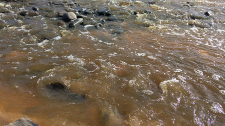 stream with muddy waters, fast flow, sandy shoreの写真素材