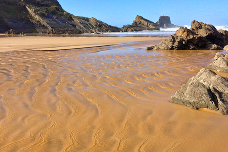 rocks on the ocean, seascape, beautiful sandy beach, clear blue sky, sunny weatherの写真素材