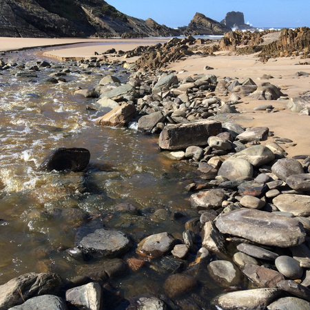 small river flows into the ocean, fast stream flows to the sea, beautiful landscape, amazing rocksの写真素材