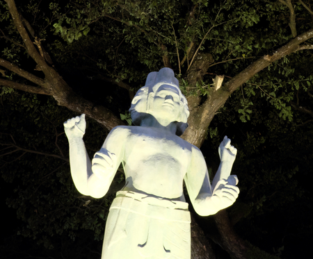 The statue of a Hindu deity with four hands and several faces, night lighting, Asian cultureの写真素材