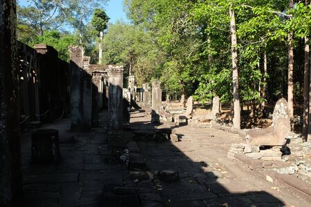 Ruins of a medieval temple in Southeast Asia. Abandoned stone buildings. Sunny weather. Tropical trees.の写真素材
