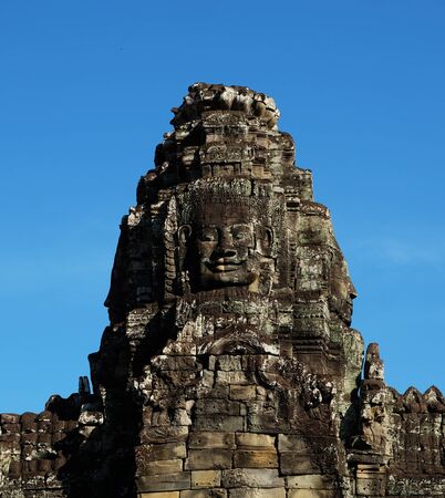 A huge human face built of stone blocks. Huge human faces on the towers of the Bayon temple in Cambodia. Architectural art of ancient civilizations.の写真素材