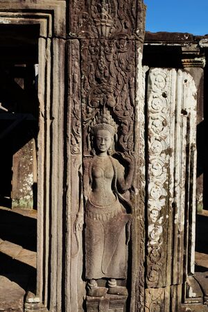 Ancient stone bas-relief on the wall of an abandoned Khmer temple. Stone sculpture of a woman.の写真素材