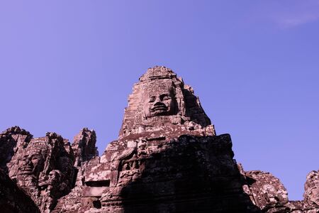 A huge human face built of stone blocks. Huge human faces on the towers of the Bayon temple in Cambodia. Architectural art of ancient civilizations.の写真素材