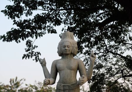 Sculpture of a four-armed Hindu deity. Mythical creature with four faces.