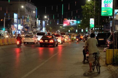 Siem Reap, Cambodia, December 23, 2018 Vehicles are waiting at the traffic light. Cyclist at night on the roadway. Night traffic of the Asian city.のeditorial素材