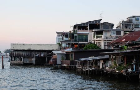 Bangkok, Thailand, December 25, 2018. Many shacks and stilt houses are located on the banks of the Chao Phraya River. Asian slum in the evening.のeditorial素材
