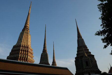 The spiers of the temple complex Wat Pra rise in the blue sky in the evening.