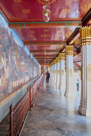 Bangkok, Thailand, December 27, 2018. A long corridor decorated with wall paintings. Part of a Buddhist temple. A man goes into the distance along the corridor.のeditorial素材