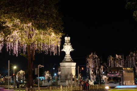 Bangkok, Thailand, December 26, 2018. A sculptural image of elephants on a street of a night city surrounded by garlanded trees.のeditorial素材