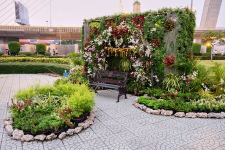 Bangkok, Thailand, December 28, 2018. An empty bench in a city park. Beautiful flowers grow in the park.のeditorial素材