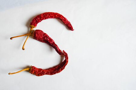 Letter S lined with red peppers on a white background. Symbol in the form of the letter S. Pepper lined in the letter S on a white background.の写真素材