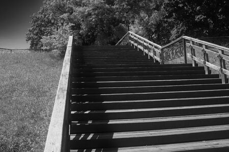Old wooden staircase in the city park of Chernigov. Way up. Black and white image.