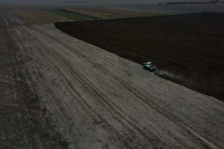 Tractor plows a field, aerial view. Agricultural landscape.