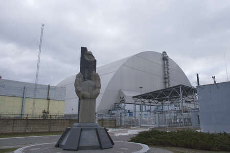 Pripyat, Ukraine, March 14, 2020. Monument to the liquidators of the accident at the Chernobyl nuclear power plant against the background of a protective sarcophagus.のeditorial素材