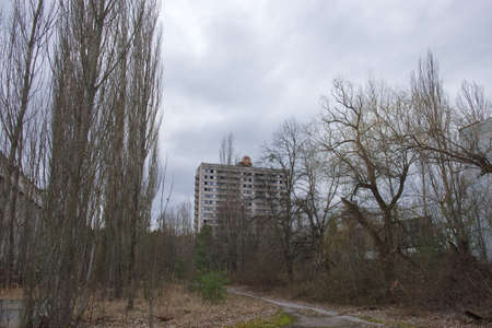 Abandoned high house in the ghost town of Pripyat. An abandoned city overgrown with trees. The area is contaminated with radiation. Coat of arms of the Soviet republic on the roof of the building.の写真素材