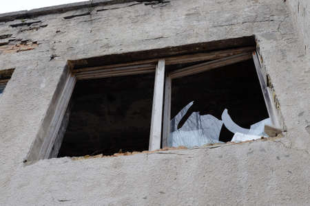 Broken window glass. Old window frame. Fragment of the building wall.の写真素材