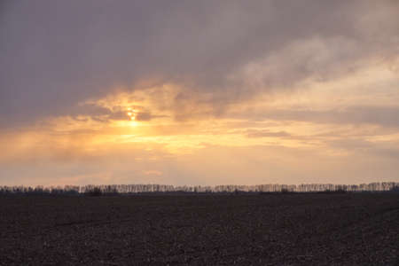 Sunset over a plowed agricultural field. Dramatic sky in the evening.