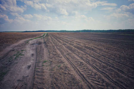 Beautiful sky over a plowed agricultural field. Agro-industrial landscape. A plowed farm field....