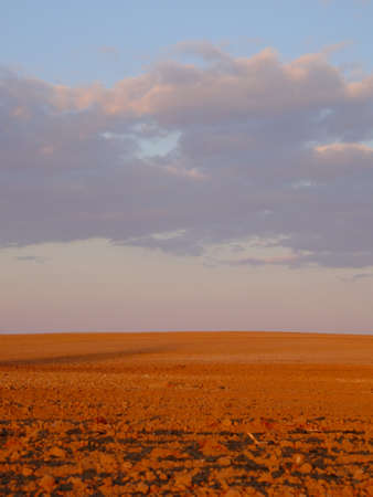 Cloudy evening sky over an empty agricultural field. Bright sunset landscape.の写真素材