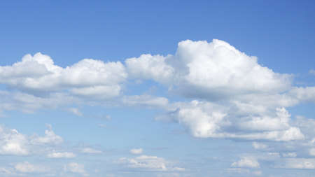 Cumulus white clouds against a clear blue sky in sunny weather. Background.