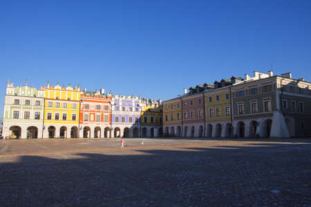 Zamosc, Poland, December 27, 2020. Little child alone on a large city square on a winter morning. Ancient European architecture, cityscape. Great Market Square. Clear blue sky over the old city.のeditorial素材