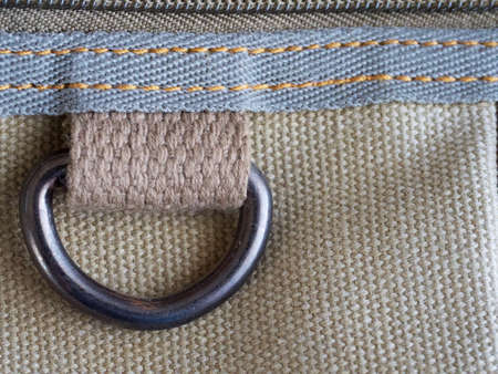 A metal buttonhole is sewn to the thick fabric. Fabric, texture.