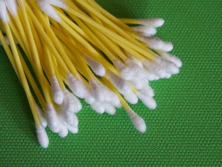 A large number of cotton swabs on a green background, a close-up shot. Cotton swabs or cotton buds....