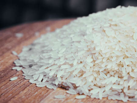 A pile of rice on a wooden surface, a close-up shot.の写真素材