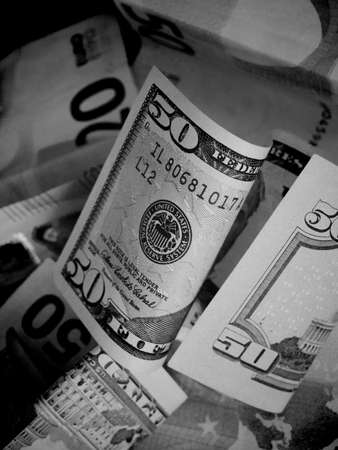 Cash banknotes dollars and euros are mixed up, a close-up shot. Black and white image.