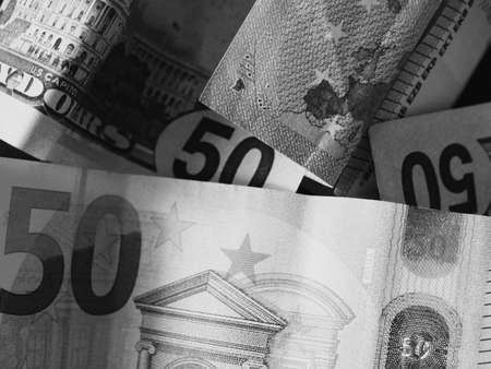 Paper banknotes in denominations of 50 dollars and 50 euros, a close-up shot. Black and white image.