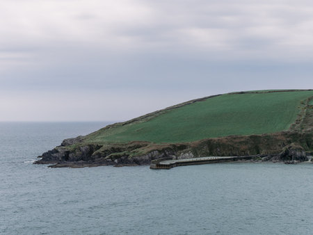 View of the coastal cliffs from the Warren beach. The rocky coast of the south of Ireland. Hills...