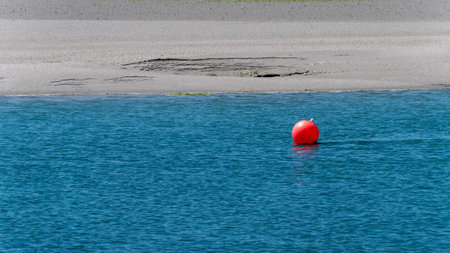 One orange sea buoy on the surface of blue water. Seascape, a copy space. red ball on blue sea waterの写真素材