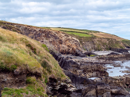 picturesque landscape. Wild vegetation on stony soil. Cloudy sky, ocean. Views on the wild Atlantic way, hills under clouds.の写真素材