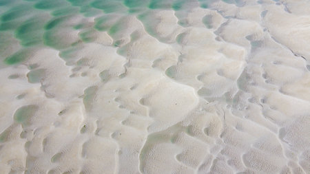 Wet beach sand at low tide, top view, texture.の写真素材
