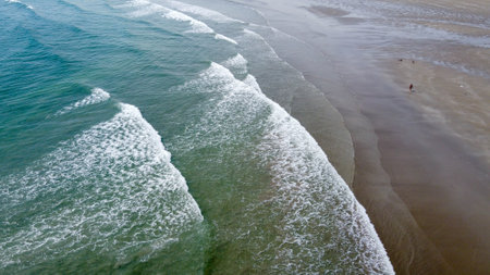 Wet coastal sand and sea waves, top view. Sandy beach and ocean tide.の写真素材