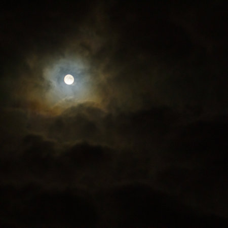The full moon shines among the clouds in the night sky. full moon in the skyの写真素材