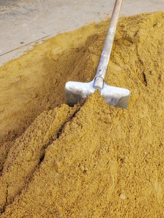 A shovel sticks out in a pile of sand.の写真素材