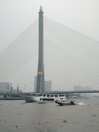 Bangkok, Thailand, December 28, 2018. The Rama VIII Bridge in Bangkok, a cable-stayed structure with a solitary pylon, stretches across the Chao Phraya River beneath a cloudy sky.のeditorial素材