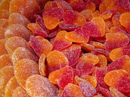 A close-up of orange and red gummy candies in the shape of hearts, covered in sugar crystals.の写真素材