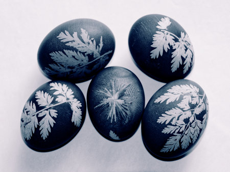 Five eggs with leaf patterns on a white surface.