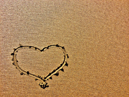 A heart is etched into a sandy surface, showing a clear contrast.の写真素材
