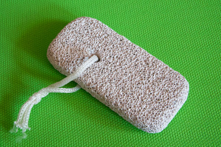 Skincare Tool Display. Pumice stone with string, presented on vibrant green, highlighting its exfoliating texture.の写真素材