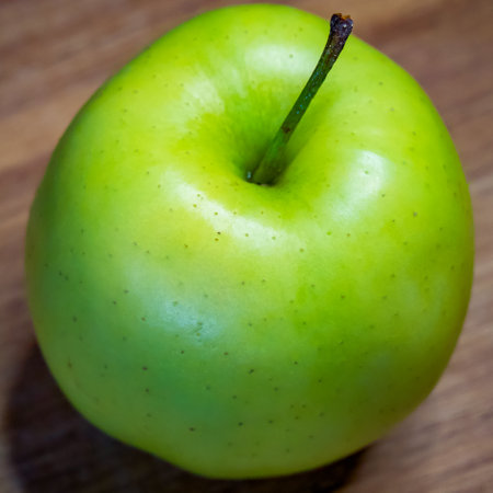 The wooden surface beneath the apple adds a rustic, organic feel.の写真素材