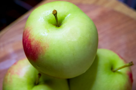 Organic Apple Display. Green apples, one in focus, on a rustic wood backdrop.の写真素材